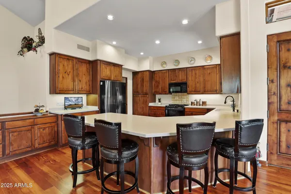 a kitchen with stainless steel appliances kitchen island granite countertop a dining table chairs and a refrigerator