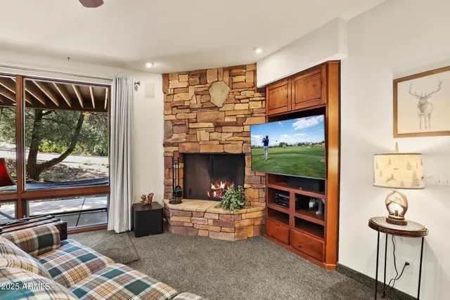 a living room with furniture a flat screen tv and a floor to ceiling window