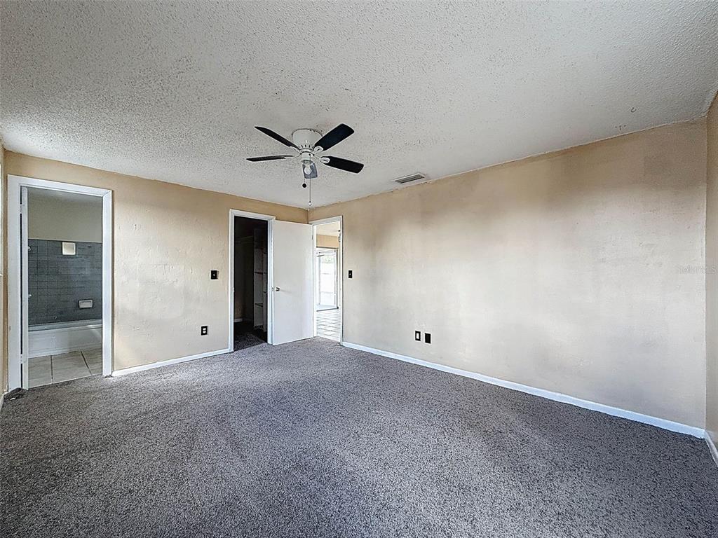 9381 Marler Road Spring Hill, FL 34608 - Photo 17 of 52 an empty room with a ceiling fan and windows