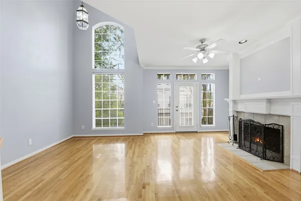 a view of an empty room with wooden floor fireplace and a window