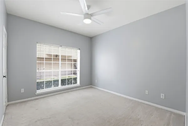 an empty room with a ceiling fan and windows
