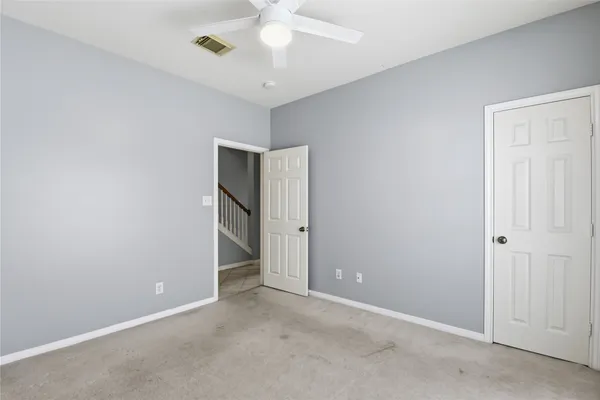 an empty room with a chandelier fan and closet area
