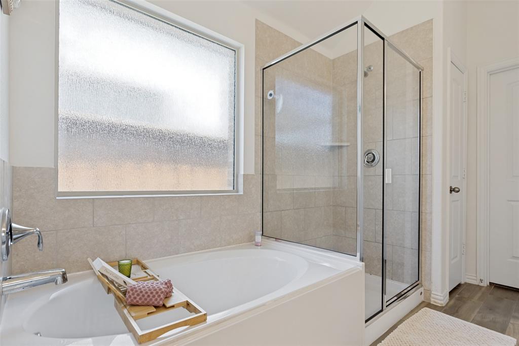 5556 Vaquero Road Fort Worth, TX 76126 - Photo 17 of 25 Bathroom featuring a built-in tub with chrome fixtures, a frosted window for tons of natural light, and a glass-enclosed shower with a tiled surround