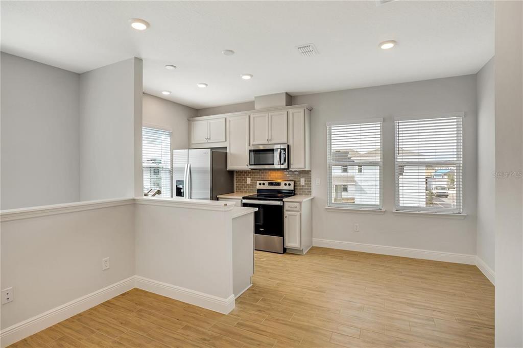 6547 Rover Way St. Cloud, FL 34771 - Photo 6 of 11 a kitchen with granite countertop a stove top oven a sink dishwasher and a refrigerator with wooden floor