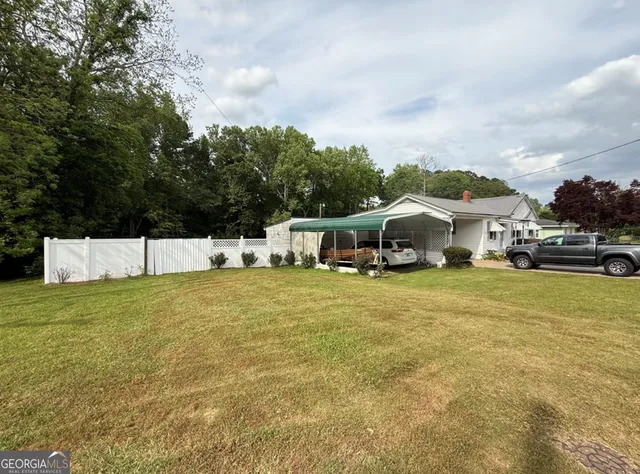 a view of a white house with a big yard and large trees