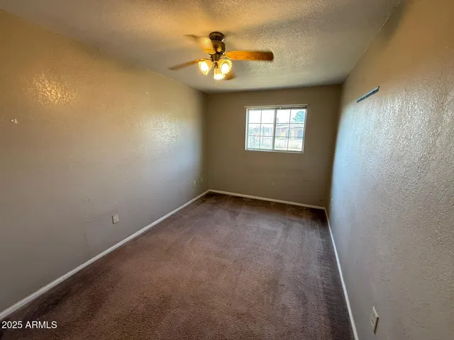 an empty room with a ceiling fan and a window