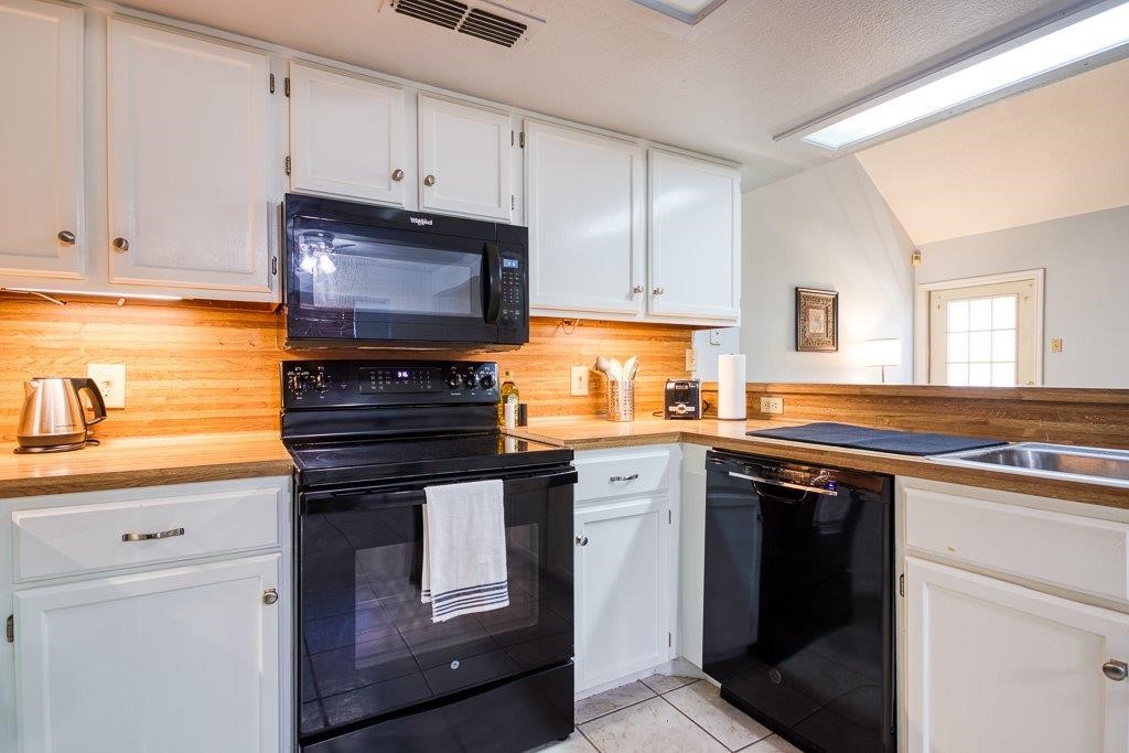 906 St Christopher Street Corpus Christi, TX 78418 - Photo 17 of 40 a kitchen with stainless steel appliances granite countertop a stove a sink and a microwave