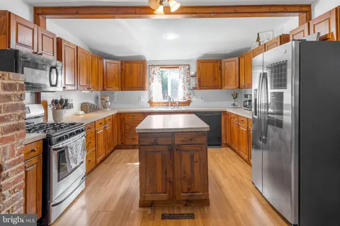 a kitchen with stainless steel appliances granite countertop a stove a sink dishwasher a refrigerator and cabinets with wooden floor