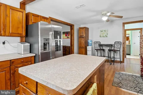 a kitchen with stainless steel appliances kitchen island granite countertop a table chairs sink and cabinets