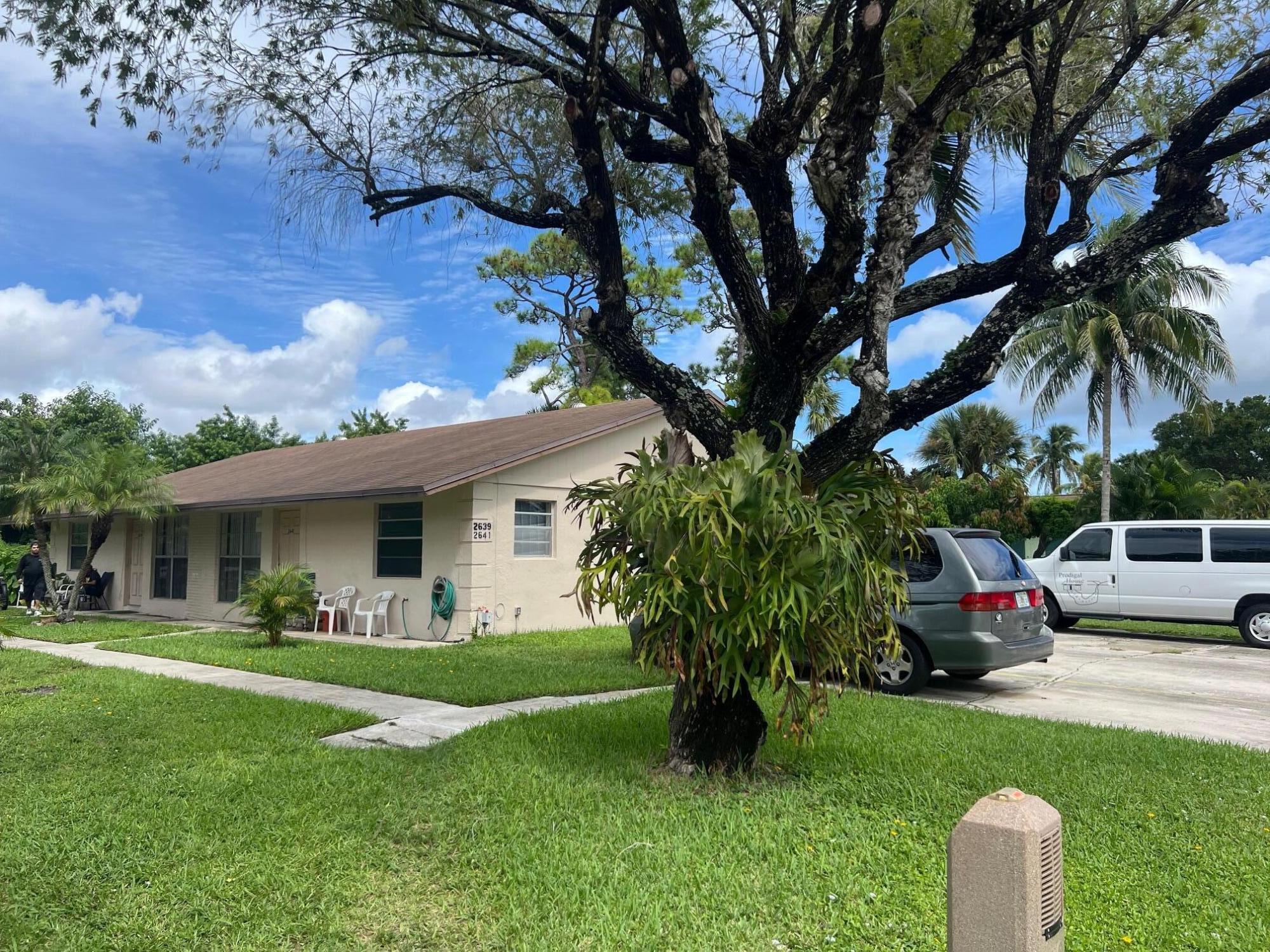2621 Southeast Clayton Street Stuart, FL 34997 - Photo 4 of 40 a front view of a house with a garden and trees