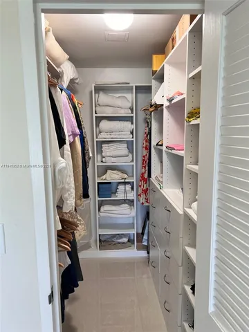a view of walk in closet with clothes and shoes