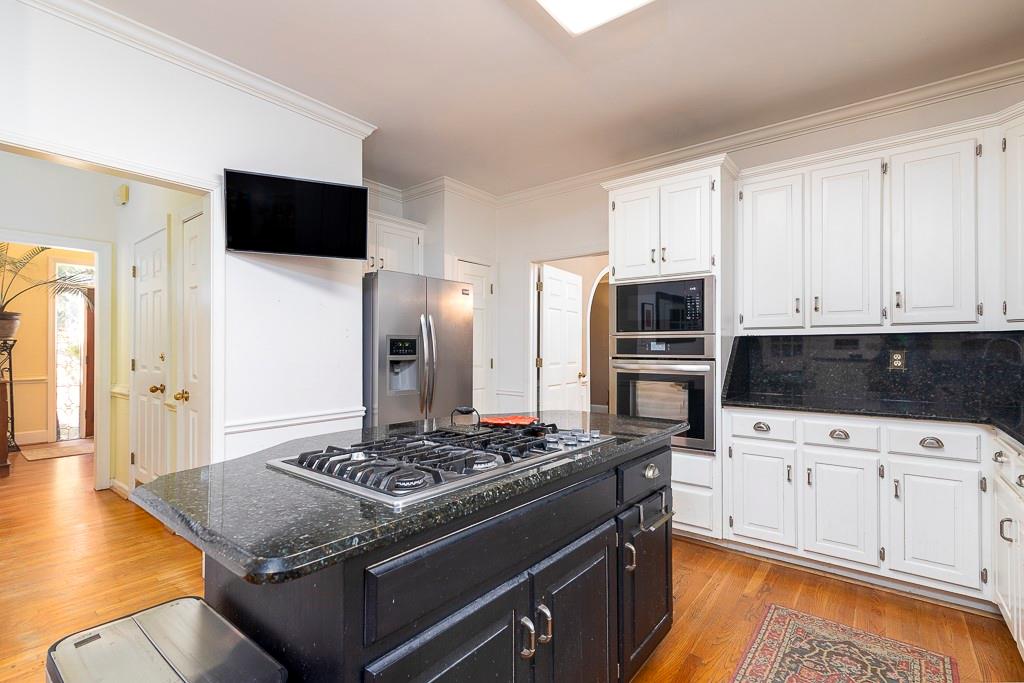 135 Lazy Laurel Chase Roswell, GA 30076 - Photo 23 of 64 a kitchen with stainless steel appliances kitchen island granite countertop a stove a sink and a microwave