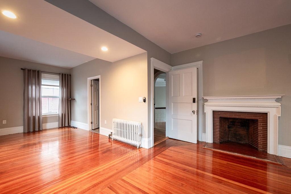 11 Wayne Street Boston, MA 02121 - Photo 10 of 27 a view of an empty room with wooden floor fireplace and a window