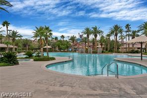 87 Tall Ruff Drive Las Vegas, NV 89148 - Photo 9 of 71 An oasis awaits with this expansive pool featuring a water slide and waterfall, surrounded by palms.