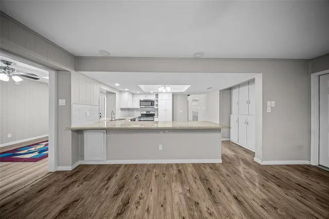 a kitchen with wooden floors and white cabinets