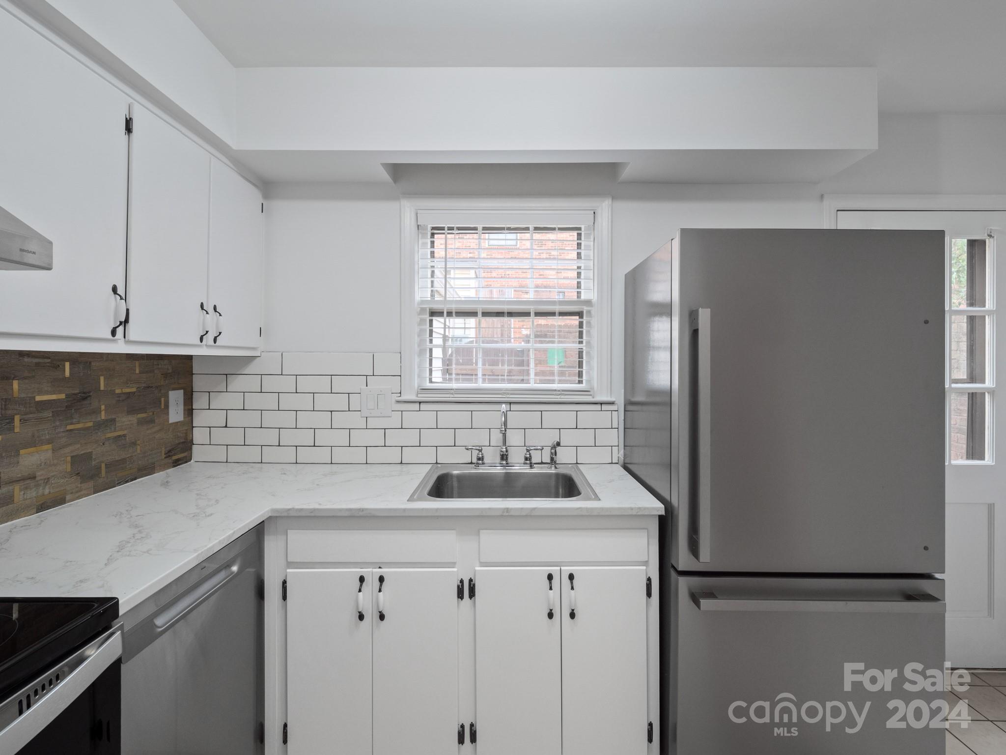 6306 Old Pineville Road, Unit B Charlotte, NC 28217 - Photo 7 of 16 a kitchen with stainless steel appliances granite countertop a refrigerator sink and white cabinets