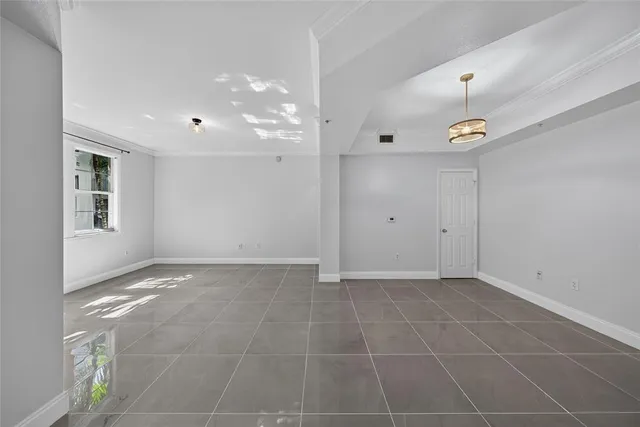 a view of an empty room and chandelier fan