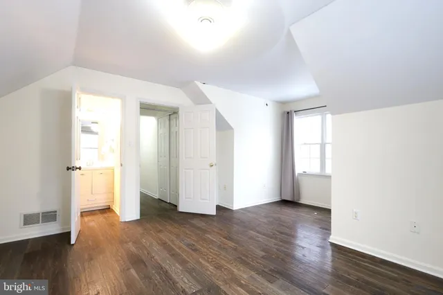 a view of a white house with a large tree with wooden fence
