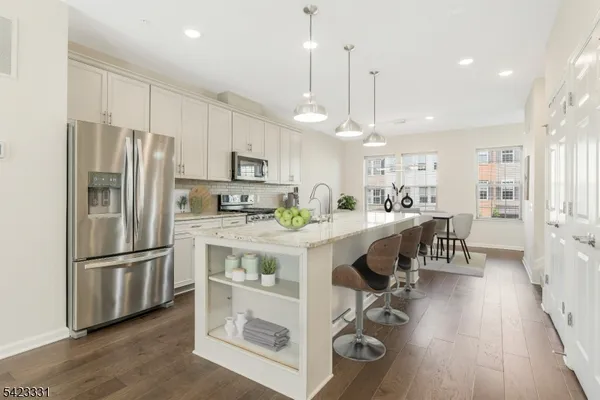 a kitchen with kitchen island a center island stainless steel appliances cabinets and a wooden floor