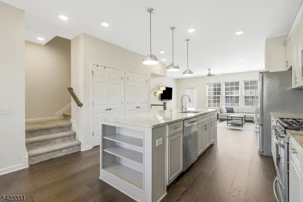 a large white kitchen with a large counter top space a sink stainless steel appliances and cabinets