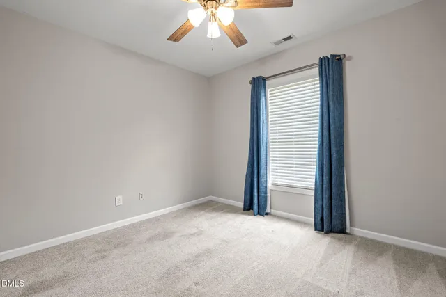 an empty room with a chandelier fan and window
