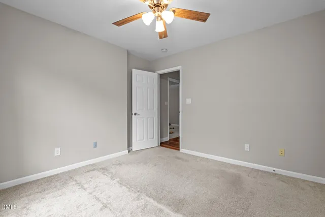 an empty room with a chandelier fan and windows