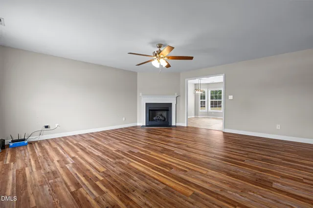 a view of an empty room with wooden floor and a fireplace
