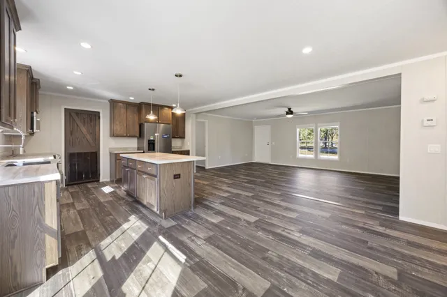 a kitchen with a sink stainless steel appliances white cabinets and wooden floor