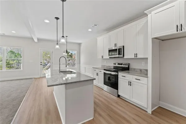 a kitchen with granite countertop a sink a counter space appliances and cabinets