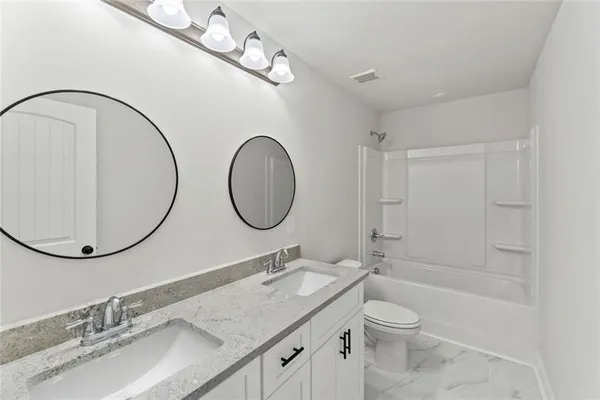 a bathroom with a granite countertop toilet a sink and a mirror