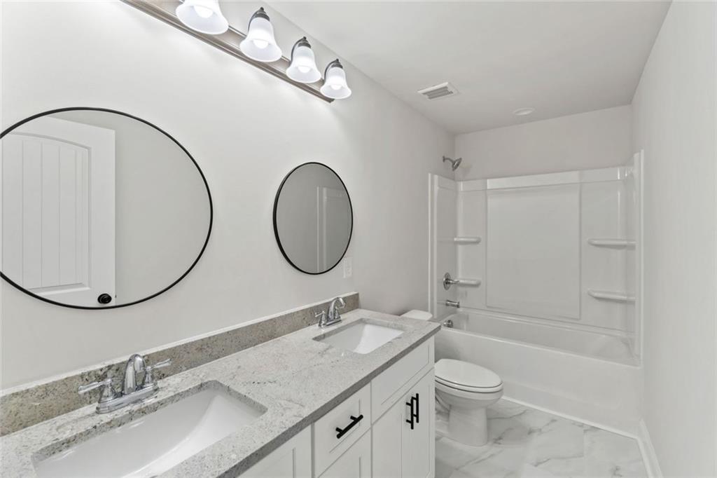 769 Dawn Place Alto, GA 30510 - Photo 28 of 40 a bathroom with a granite countertop toilet a sink and a mirror