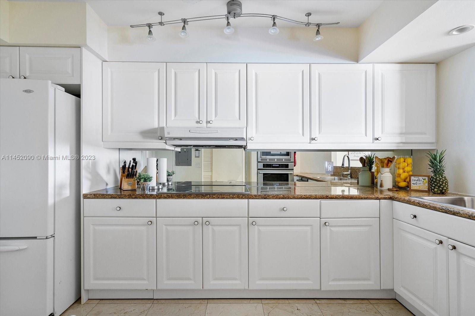8925 Collins Avenue, Unit 9J Surfside, FL 33154 - Photo 12 of 41 a kitchen with white cabinets and refrigerator
