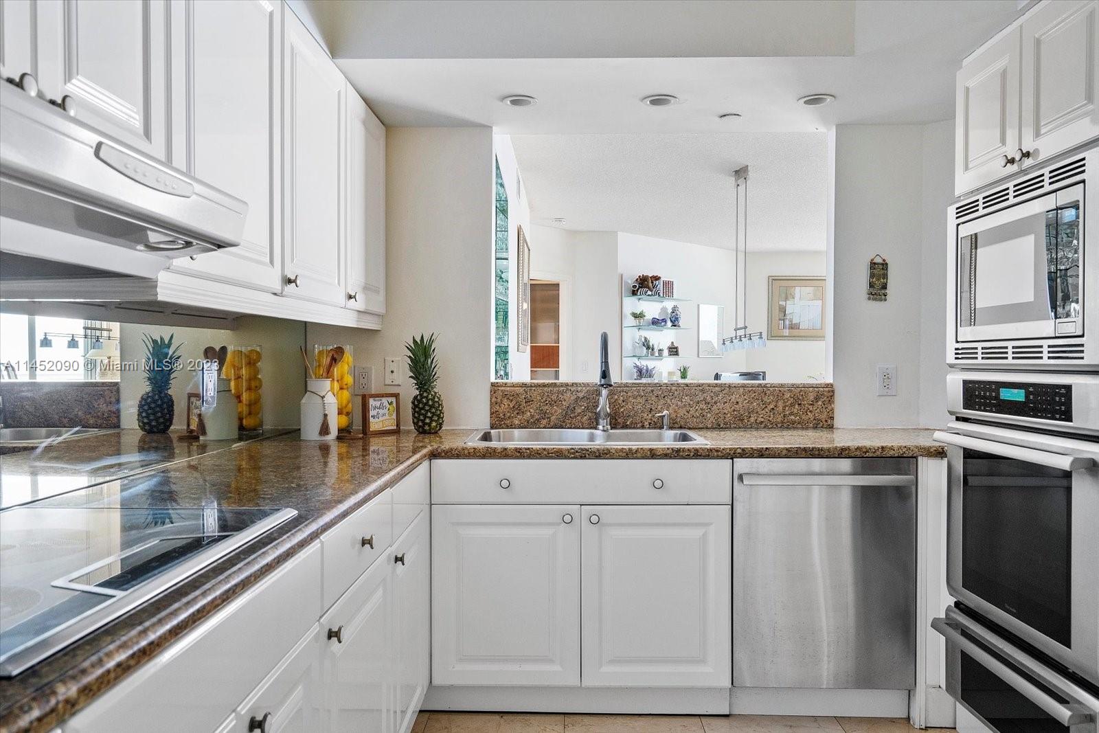8925 Collins Avenue, Unit 9J Surfside, FL 33154 - Photo 13 of 41 a kitchen with granite countertop white cabinets and stainless steel appliances