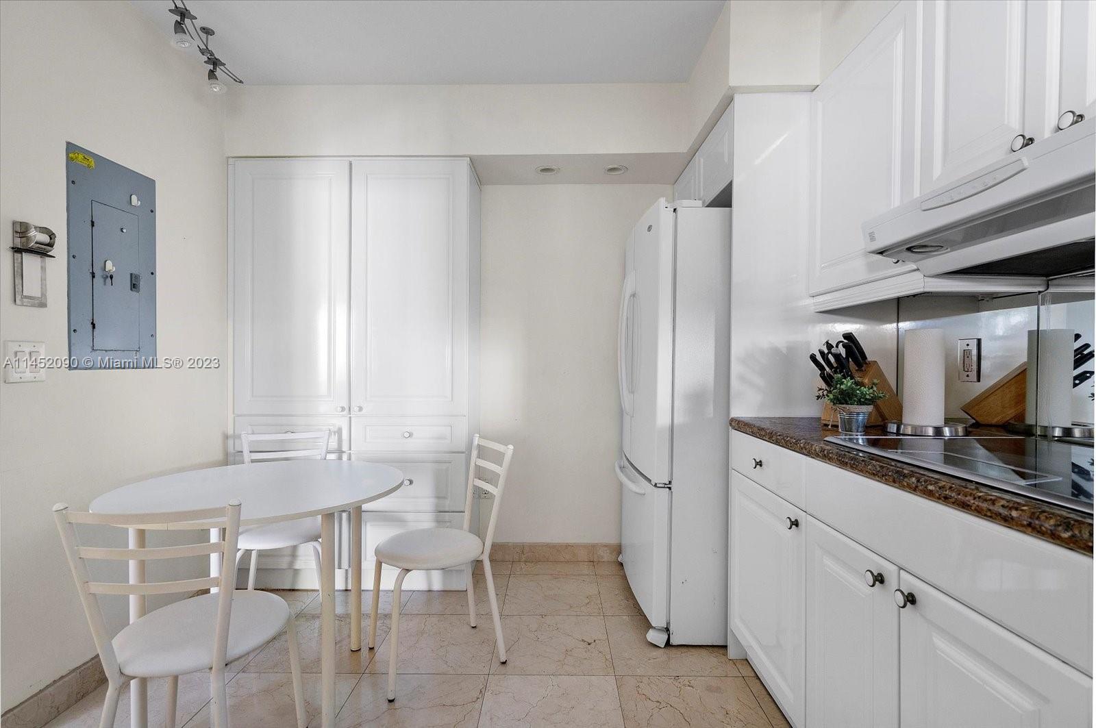8925 Collins Avenue, Unit 9J Surfside, FL 33154 - Photo 14 of 41 a kitchen with stainless steel appliances kitchen island granite countertop a table and chairs in it