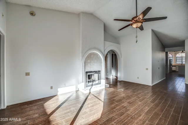 a view of a livingroom with a fireplace a ceiling fan and wooden floor
