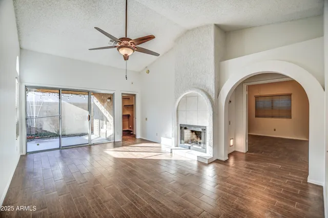 a view of empty room with wooden floor and fan