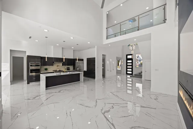 a large white kitchen with stainless steel appliances kitchen island granite countertop a refrigerator and a stove top oven