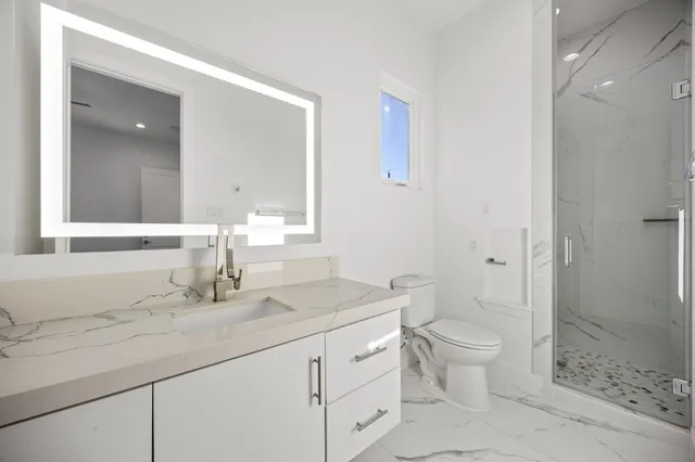 a bathroom with a granite countertop sink a toilet and shower