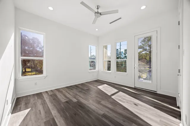 a view of an empty room with a window and wooden floor