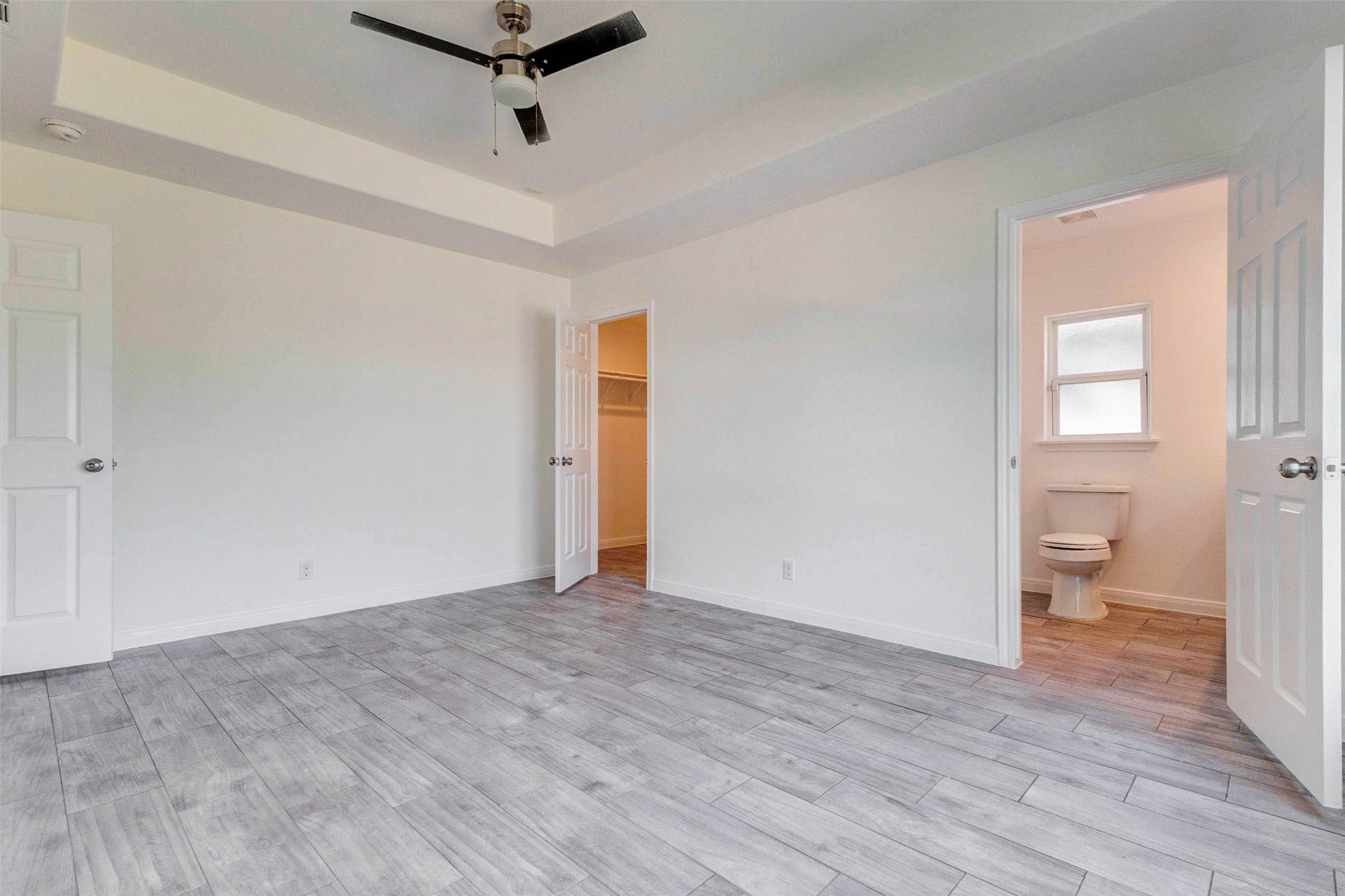 9811 Kerr Street Houston, TX 77029 - Photo 12 of 22 Spacious primary bedroom retreat featuring a beautiful tray ceiling that adds architectural interest and depth to the space. Clean, modern finishes and neutral tones create a calming atmosphere, while the durable flooring offers both style and practicality. The room flows seamlessly into a private ensuite bathroom and walk-in closet, providing convenience and comfort. Plenty of wall space allows for flexible furniture arrangements to suit any lifestyle.