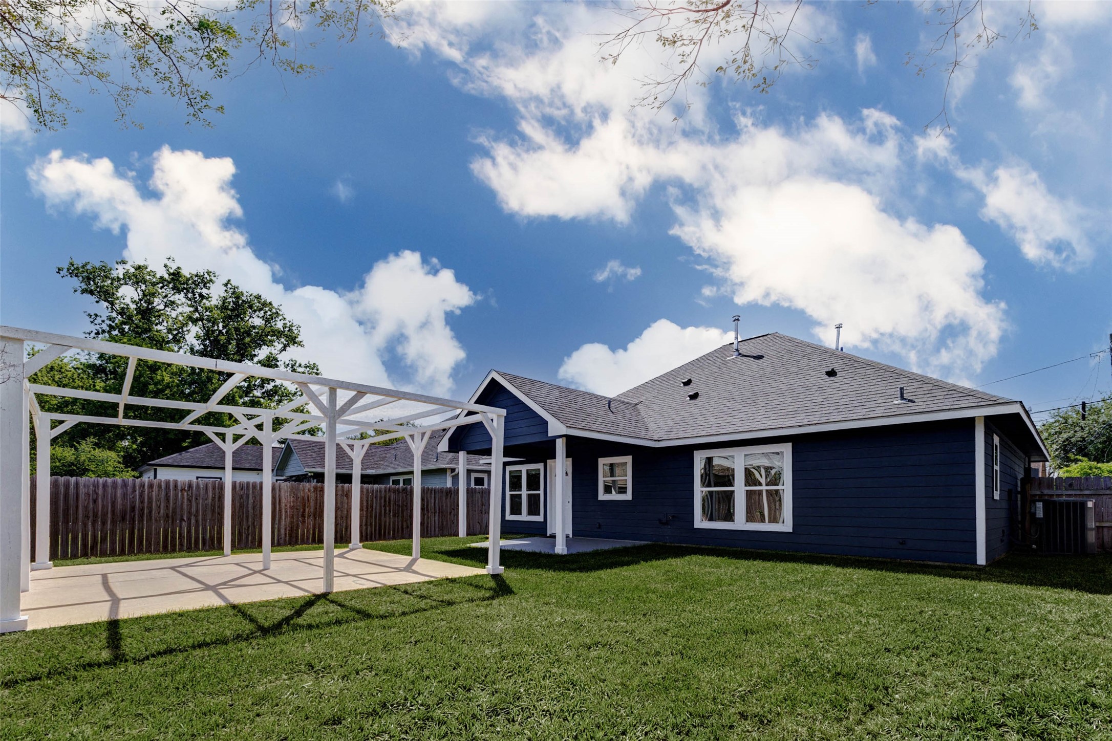 9811 Kerr Street Houston, TX 77029 - Photo 20 of 22 Expansive backyard view showcasing the full rear elevation, including a covered patio and beautifully maintained green space. The pergola adds character and functionality, creating a designated area for outdoor dining or lounging. With ample yard space and privacy fencing, this outdoor area offers endless possibilities for relaxation, recreation, and customization.