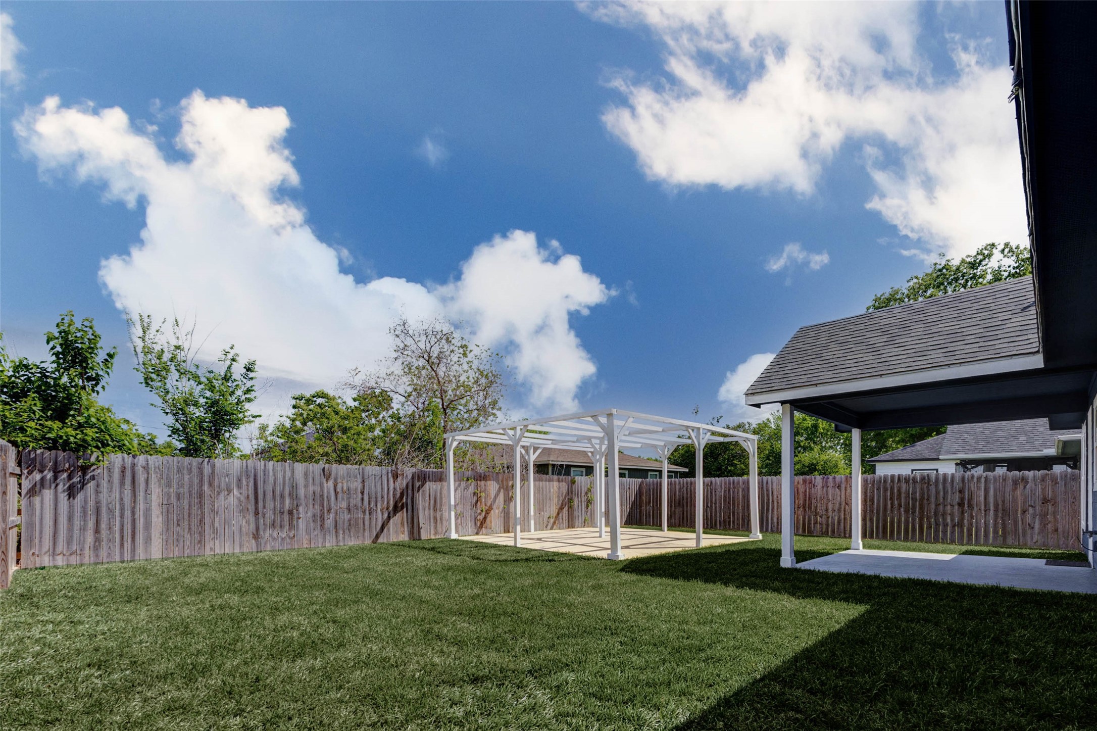 9811 Kerr Street Houston, TX 77029 - Photo 21 of 22 Another perspective of the spacious backyard highlighting the versatility of the outdoor setup. The pergola structure provides a focal point for entertaining, while the open lawn area offers room to expand, garden, or play. The home’s rear covered patio adds additional shaded seating space, making this backyard both practical and inviting.