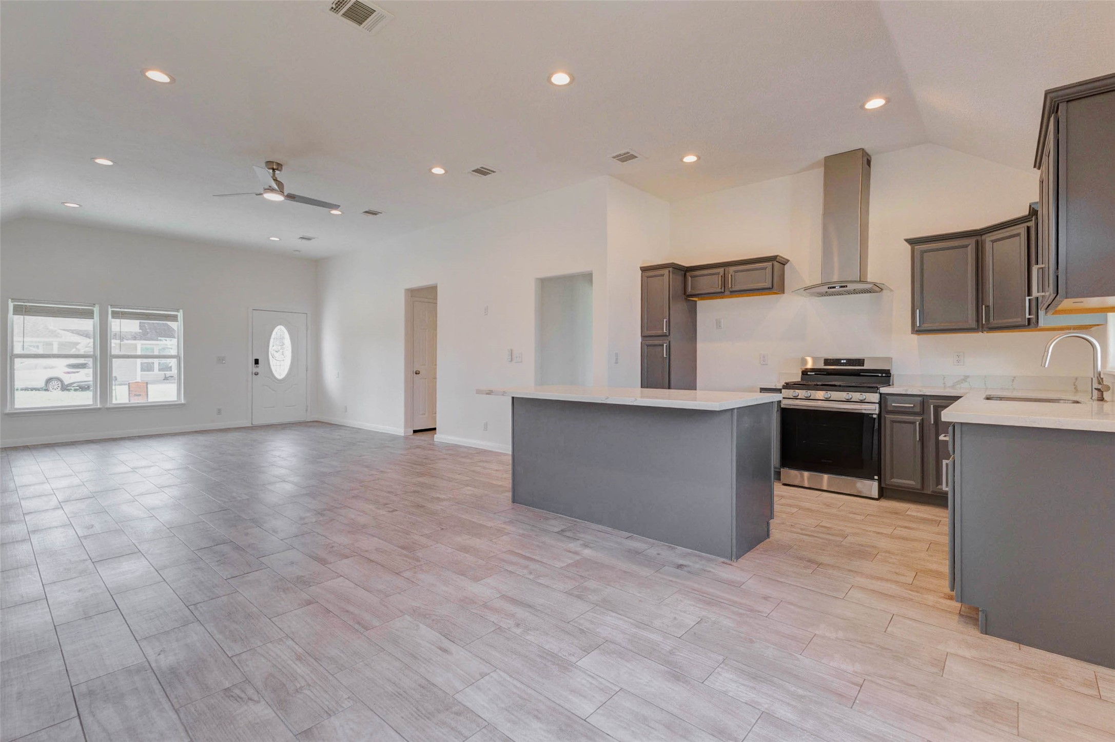 9811 Kerr Street Houston, TX 77029 - Photo 7 of 22 Expansive open-concept layout showcasing the seamless connection between the living area and kitchen, perfect for modern living. High ceilings with recessed lighting create a bright and airy feel, while the large island anchors the space for gathering and entertaining. Natural light pours in from the front windows, enhancing the clean finishes and spacious design that make this home both functional and inviting.