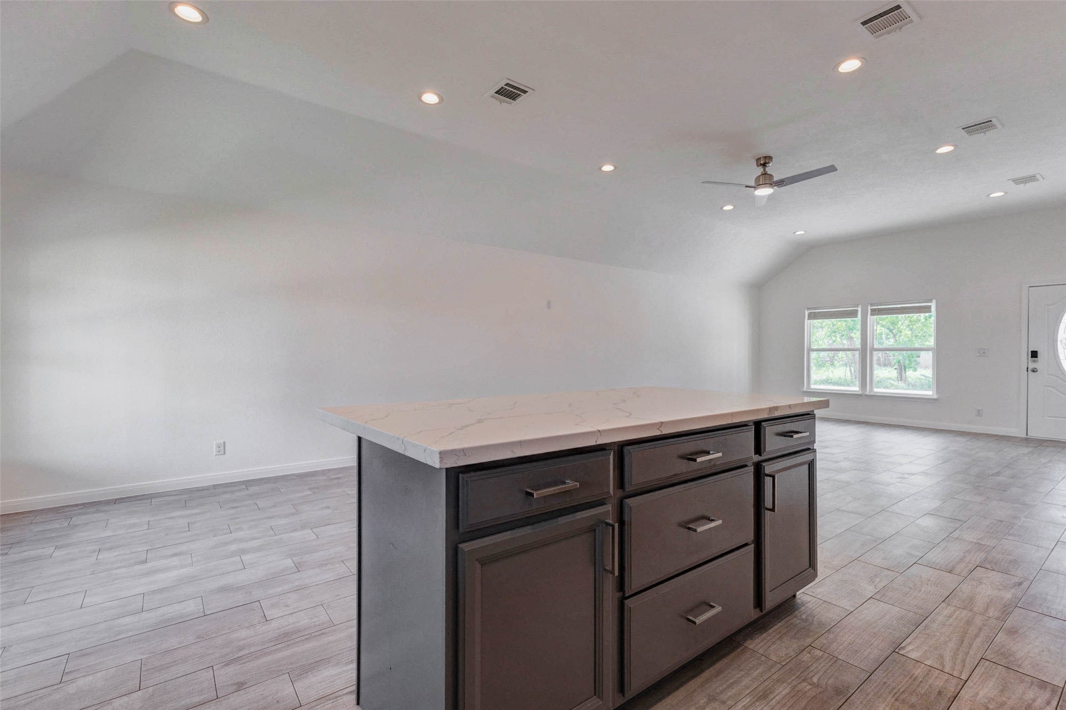 9811 Kerr Street Houston, TX 77029 - Photo 10 of 22 Oversized kitchen island with ample storage and sleek countertops serves as the centerpiece of this open-concept space. Overlooking the expansive living area, this layout is ideal for entertaining or everyday living. High ceilings, recessed lighting, and wide-open space create a welcoming environment that blends comfort and style effortlessly.