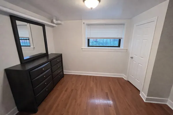 an empty room with wooden floor and fan