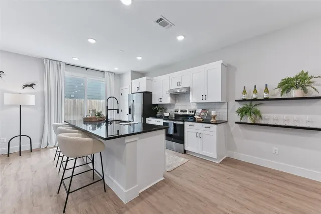 a kitchen with granite countertop white cabinets and stainless steel appliances