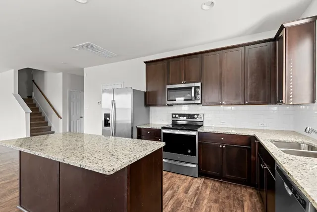 a kitchen with kitchen island granite countertop a sink stove and refrigerator