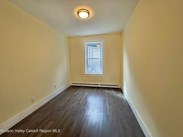 an empty room with wooden floor and mirror