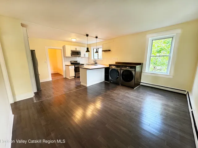 a living room with hard wood floors and a kitchen