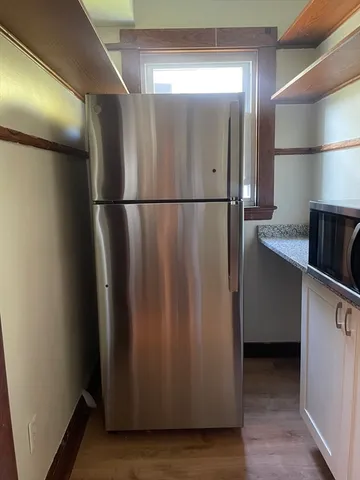 a view of a refrigerator in kitchen and an empty room